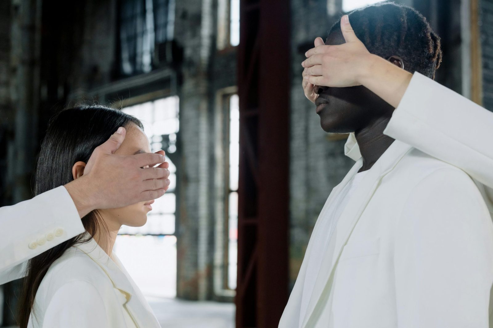 Surreal portrait of diverse people, eyes covered, in industrial setting.